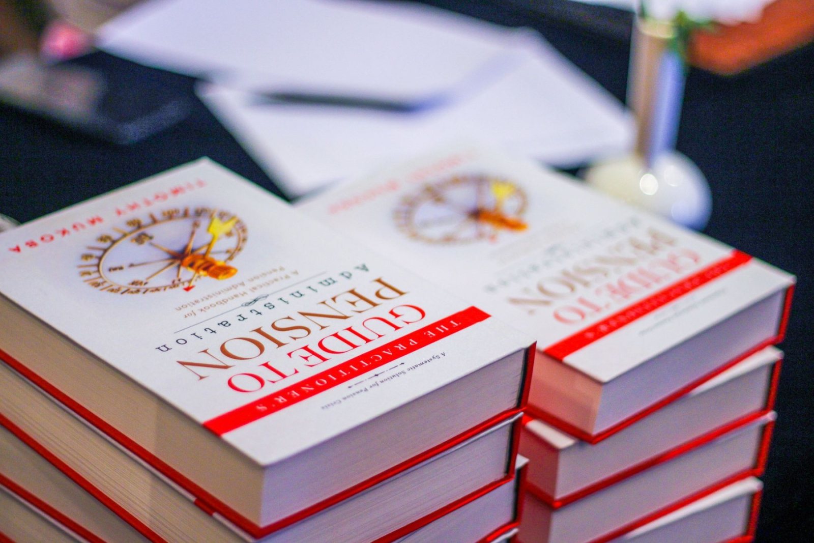 Hardcover copies of The Practitioner's Guide stacked on a table at an event